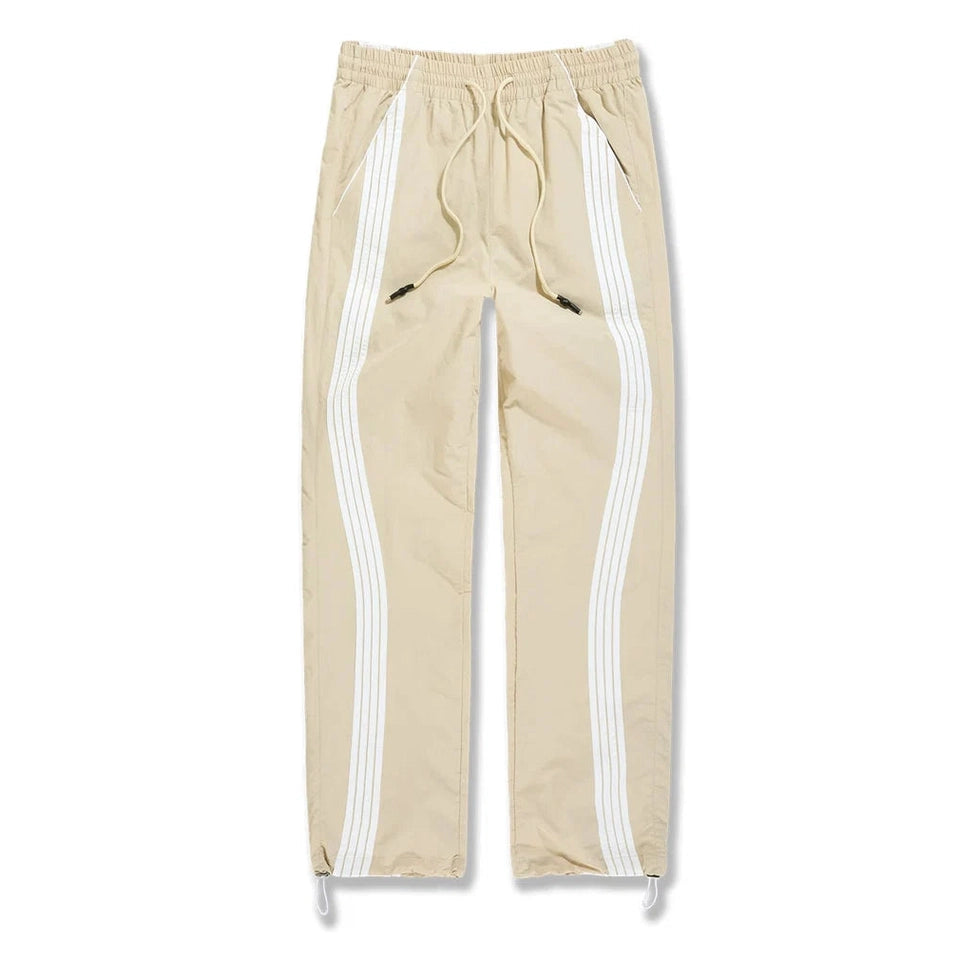 Beige Jordan Craig Big Mens The Beautiful Game track pants with white side stripes, elastic waist, drawstring, and water-resistant polyester fabric.