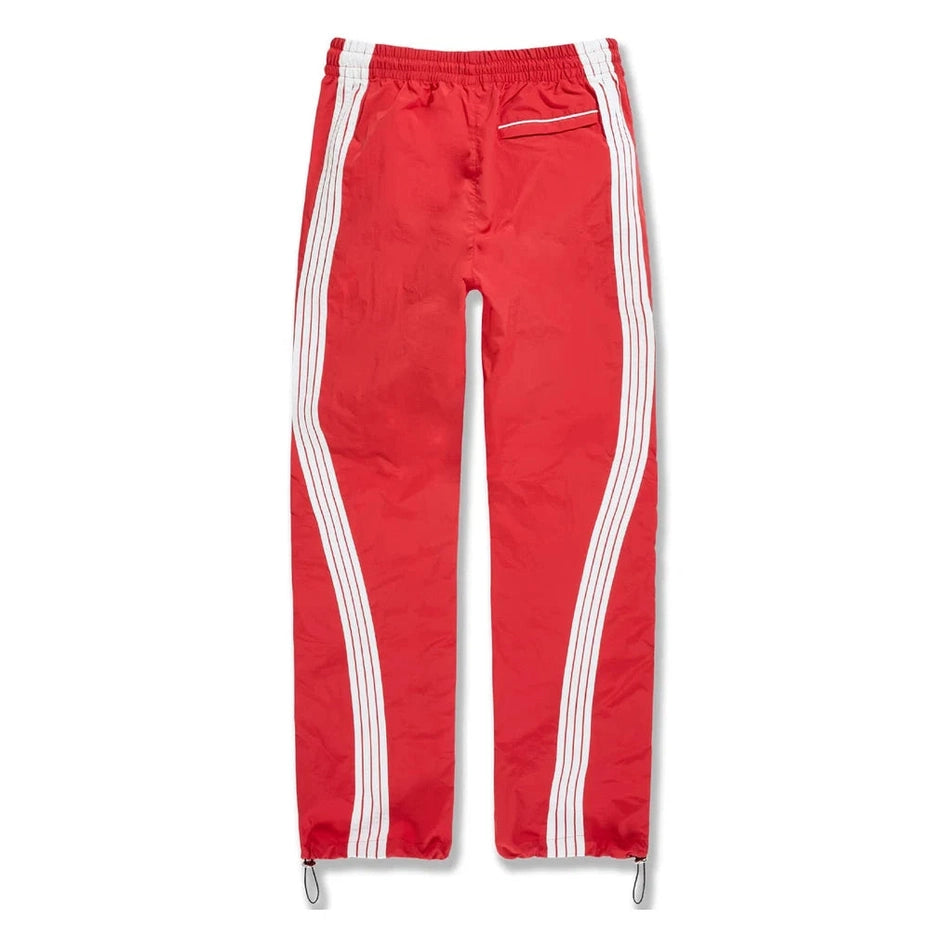 Red men's track pants with white side stripes, elastic waistband, back pocket, and drawstring ankles for active wear.