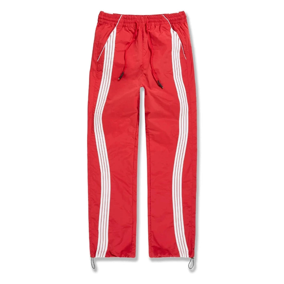 Red men's track pants with white side stripes, elastic waist, drawstring, and water-resistant polyester fabric for active wear.